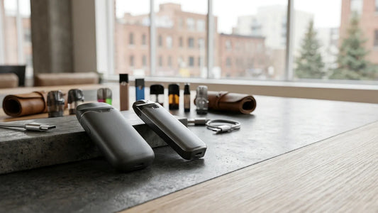 Two sleek grey vape pod systems rest on a stone surface in a bright room, showcasing modern Canadian vaping technology.