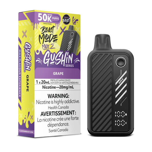 A Beast Mode Max 2 Gushin Grape disposable vape device stands next to its yellow and purple packaging, which features the Flavour Beast logo, a 50k puff count, and a 20mg/mL nicotine warning label, while the black device displays a digital screen showing battery and liquid levels.