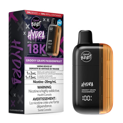 A Flavour Beast Hydra Groovy Grape Passionfruit disposable vape kit stands next to its black and purple retail box, which features a 20mg/mL nicotine warning and a 18,000 puff capacity label, against a plain black background.