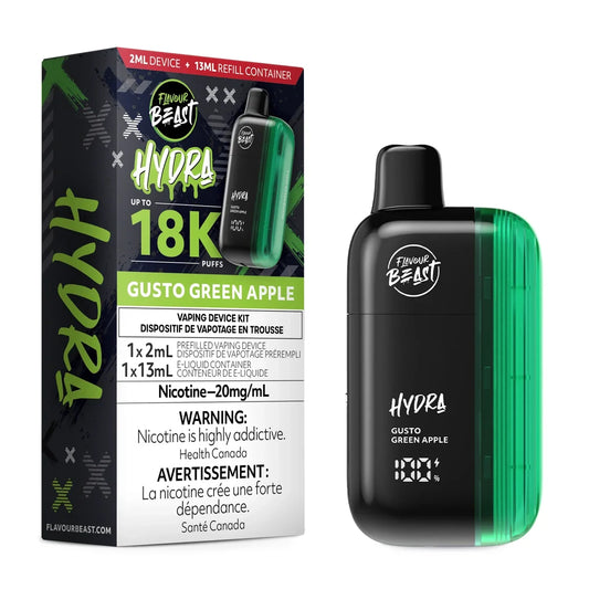 A Flavour Beast Hydra Gusto Green Apple vaping device stands next to its black and green packaging, which displays the product name, a 18K puff count, and mandatory nicotine warning labels.